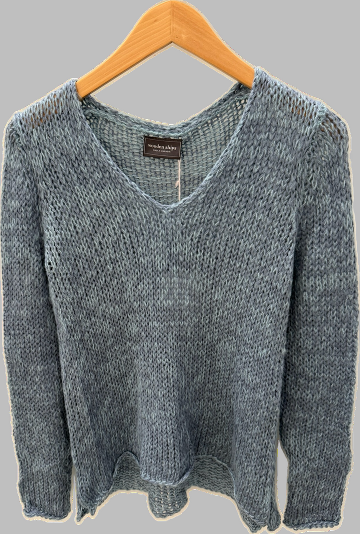 blue textured sweater on a wooden hanger against a pale grey background