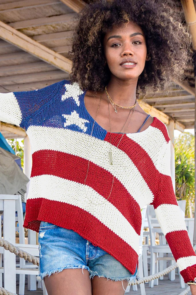 woman in v-neck flag sweater by wooden ships