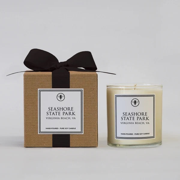Ella B. Candles neighborhood candles in a glass jar with a lit wick, showcasing warm ambient lighting and decorative design.
