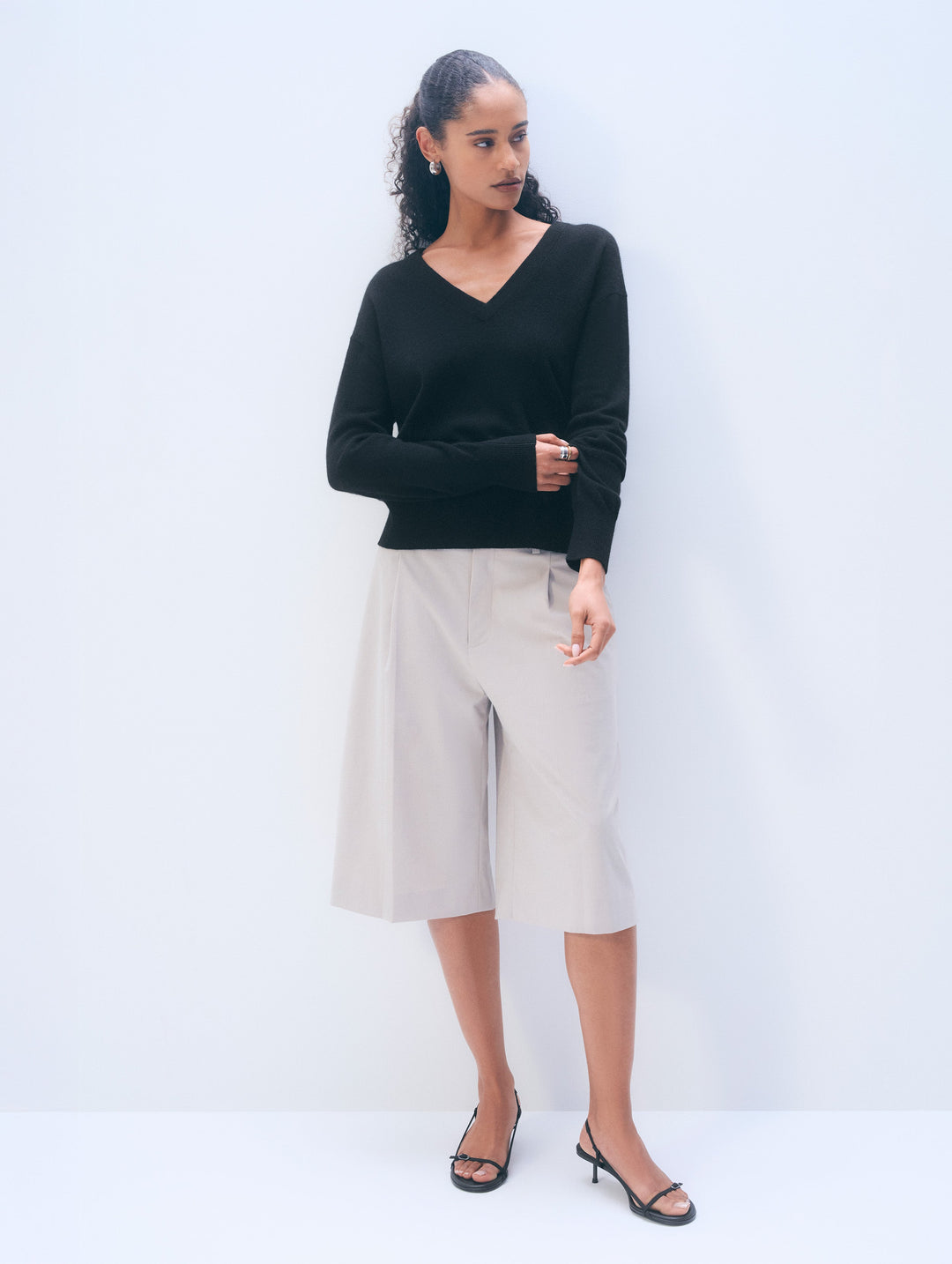 Black cashmere V-neck sweater by White & Warren, shown on a hanger with a close-up of soft, luxurious knit fabric.