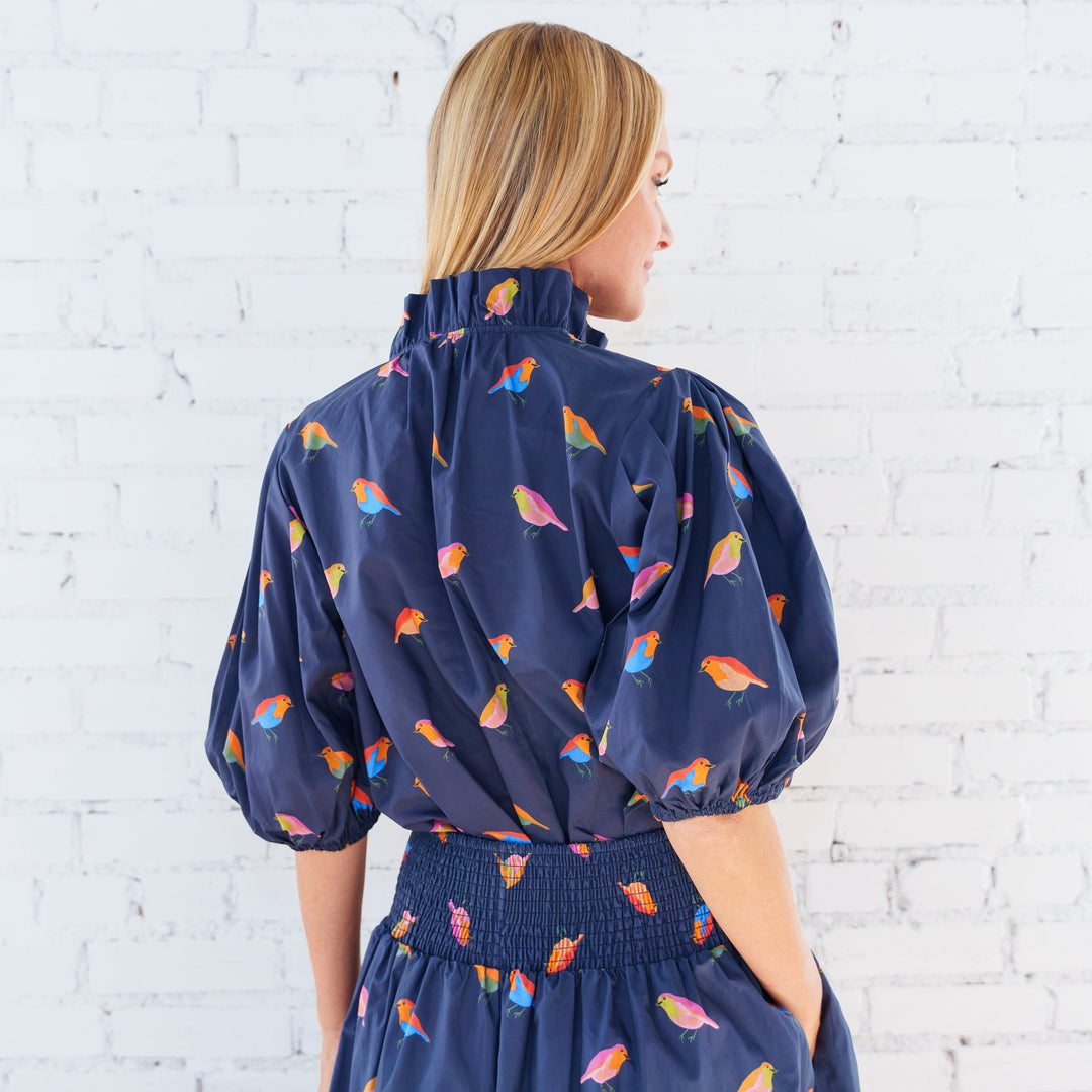 Caryn Lawn Anna Bird Top, a stylish women's blouse with a bird print, displayed on a hanger.