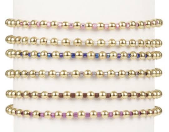 Set of gold beaded bracelets on a white background