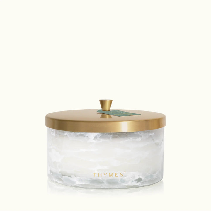 Thymes Tidings 4-wick candle in a decorative glass jar, perfect for home decor and creating a warm, festive ambiance.