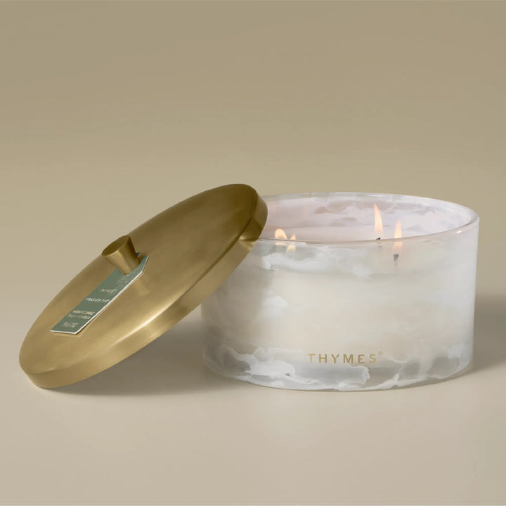 Thymes Tidings 4-wick candle in a decorative glass jar with a festive label, ideal for home décor and cozy ambiance.