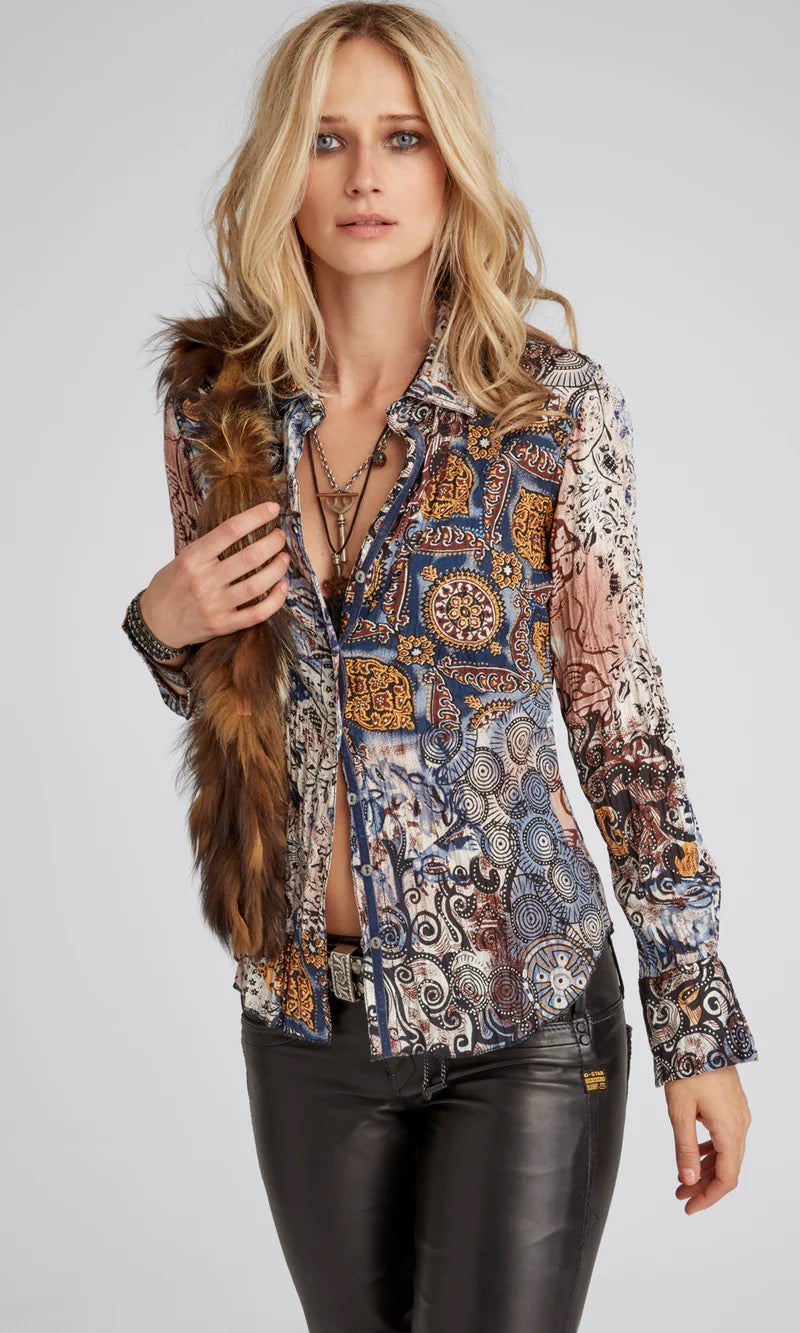 Woman wearing a patterned blouse with leather pants on a gray background
