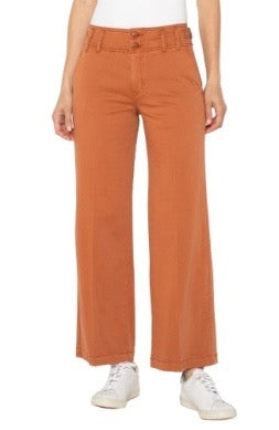 Person wearing orange pants and white sneakers on a white background