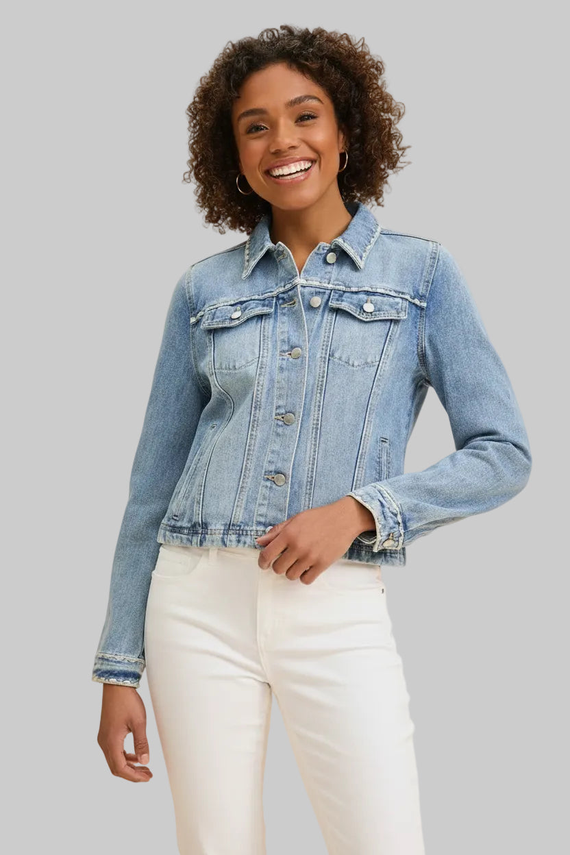 Woman wearing a light blue denim jacket and jeans on a beige background