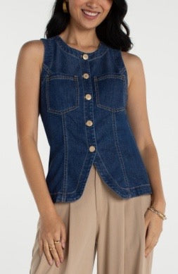 Woman wearing a denim vest over a beige top on a white background