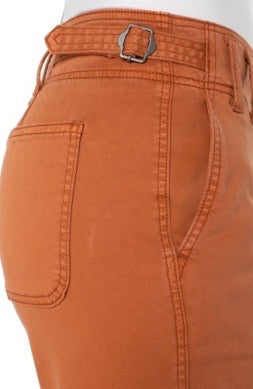Close-up of burnt orange pants with a belt and buckle on a white background