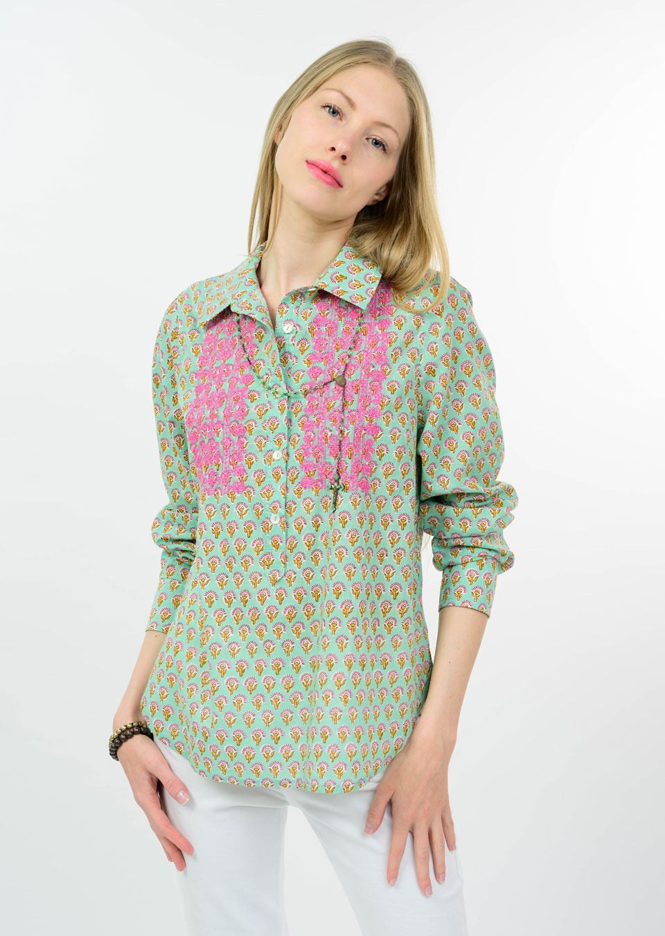 Woman wearing a patterned shirt with a pink accent on a white background