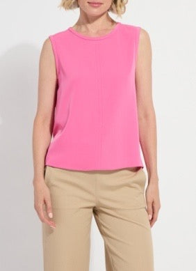 Woman wearing a pink sleeveless top and beige pants on a white background