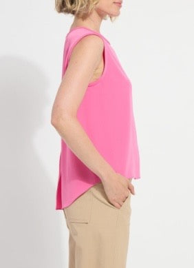 Person wearing a pink sleeveless top and beige pants on a white background