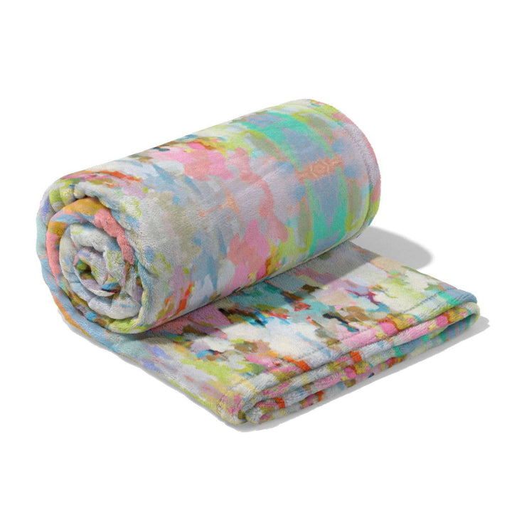 Floral-patterned blanket rolled and unfolded on a white background