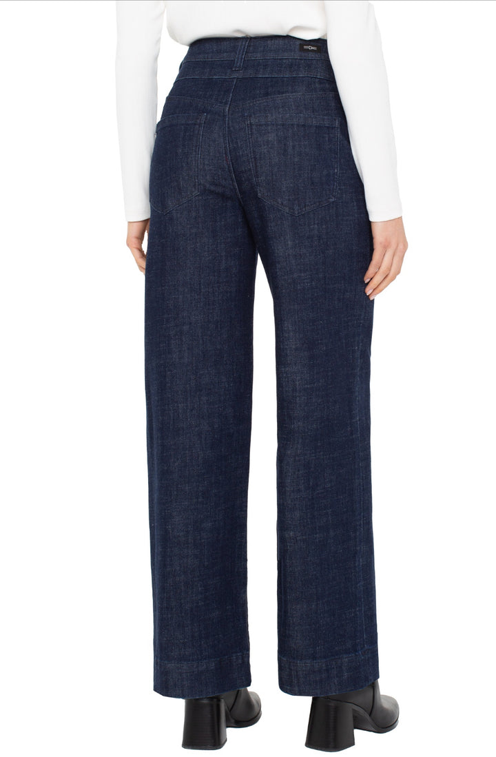 Dark blue jeans worn by a person on a white background