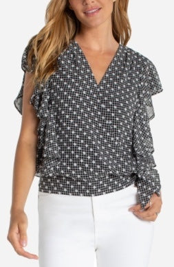 Woman wearing a black and white patterned blouse with ruffled sleeves.