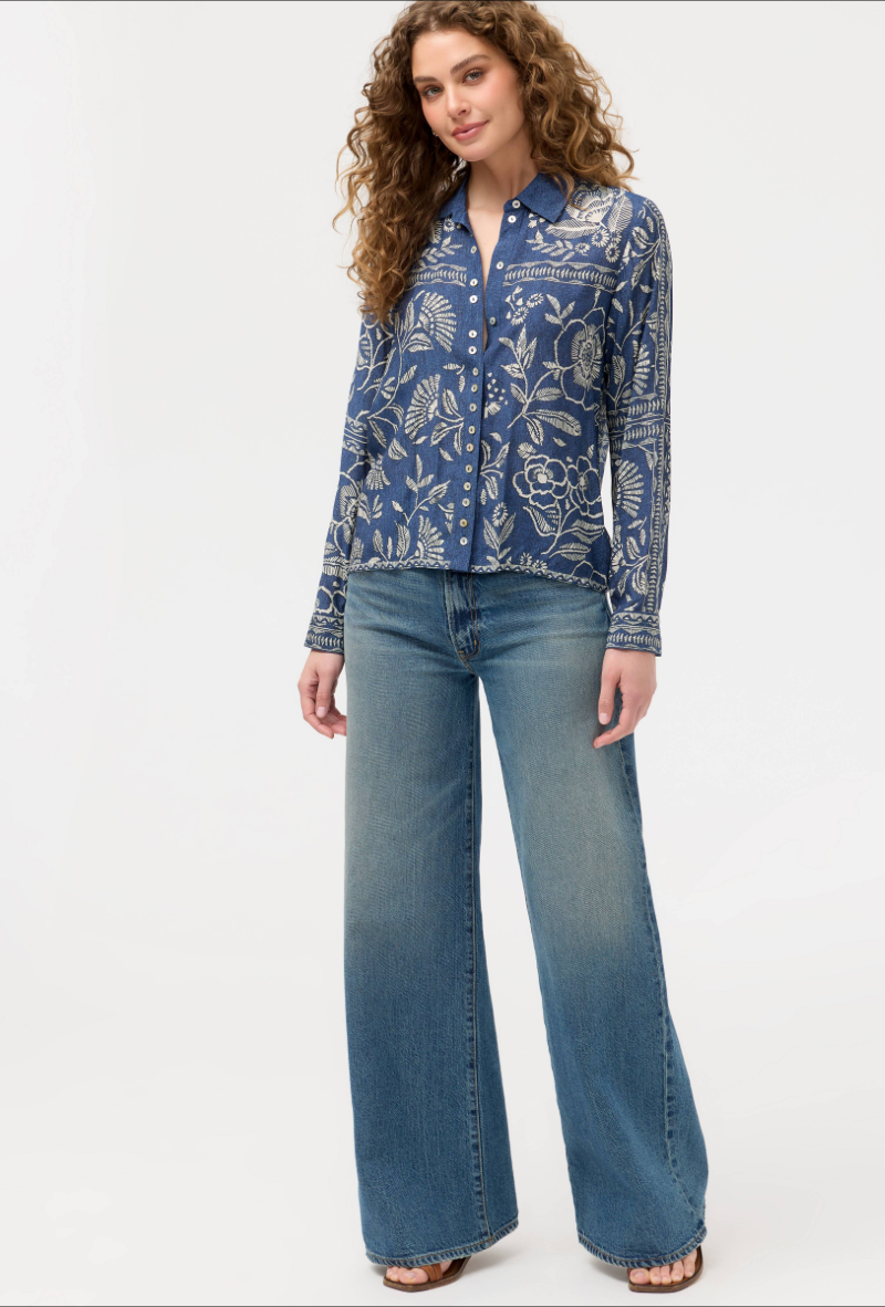 Woman wearing a blue patterned shirt and jeans on a white background