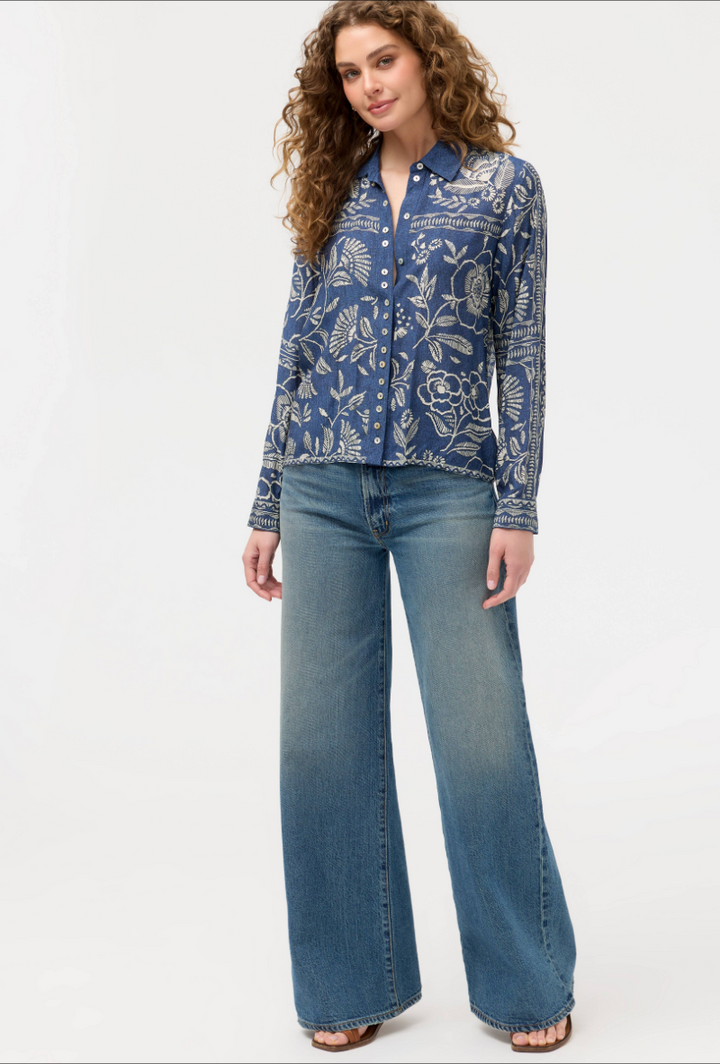 Woman wearing a blue patterned shirt and jeans on a white background