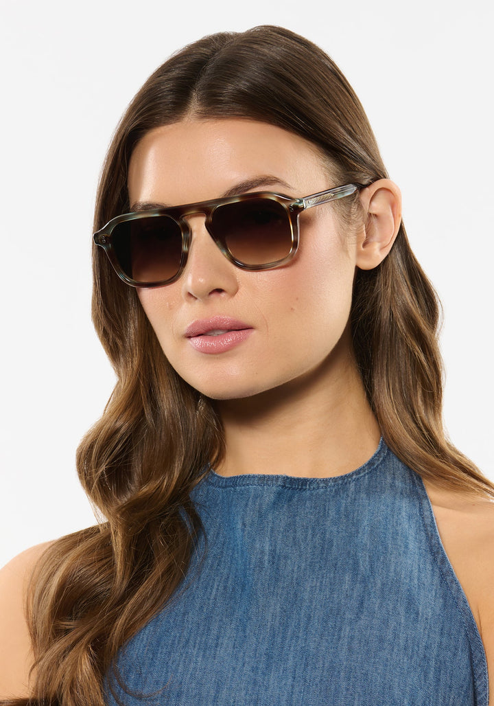 Model wearing KREWE Zander aquamarine tortoise aviator sunglasses
