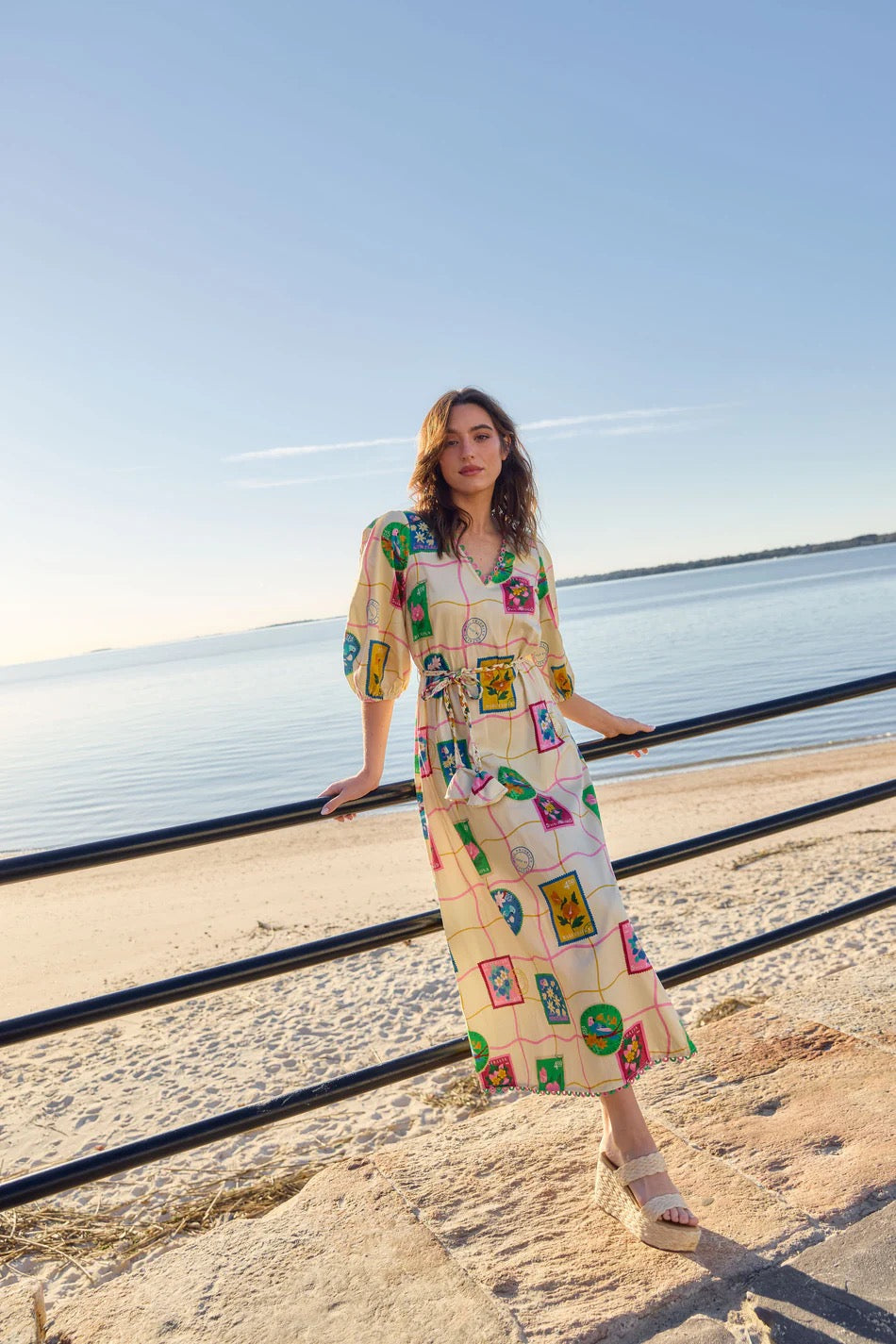 Alden Adair Lizzie Postcard Dress shown on a model, featuring a colorful, patterned design with a fitted waist and flowing skirt.