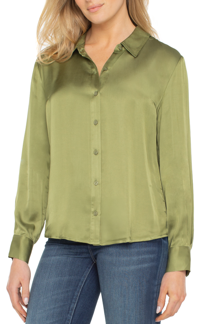 Woman wearing a green button-up shirt and blue jeans on a white background