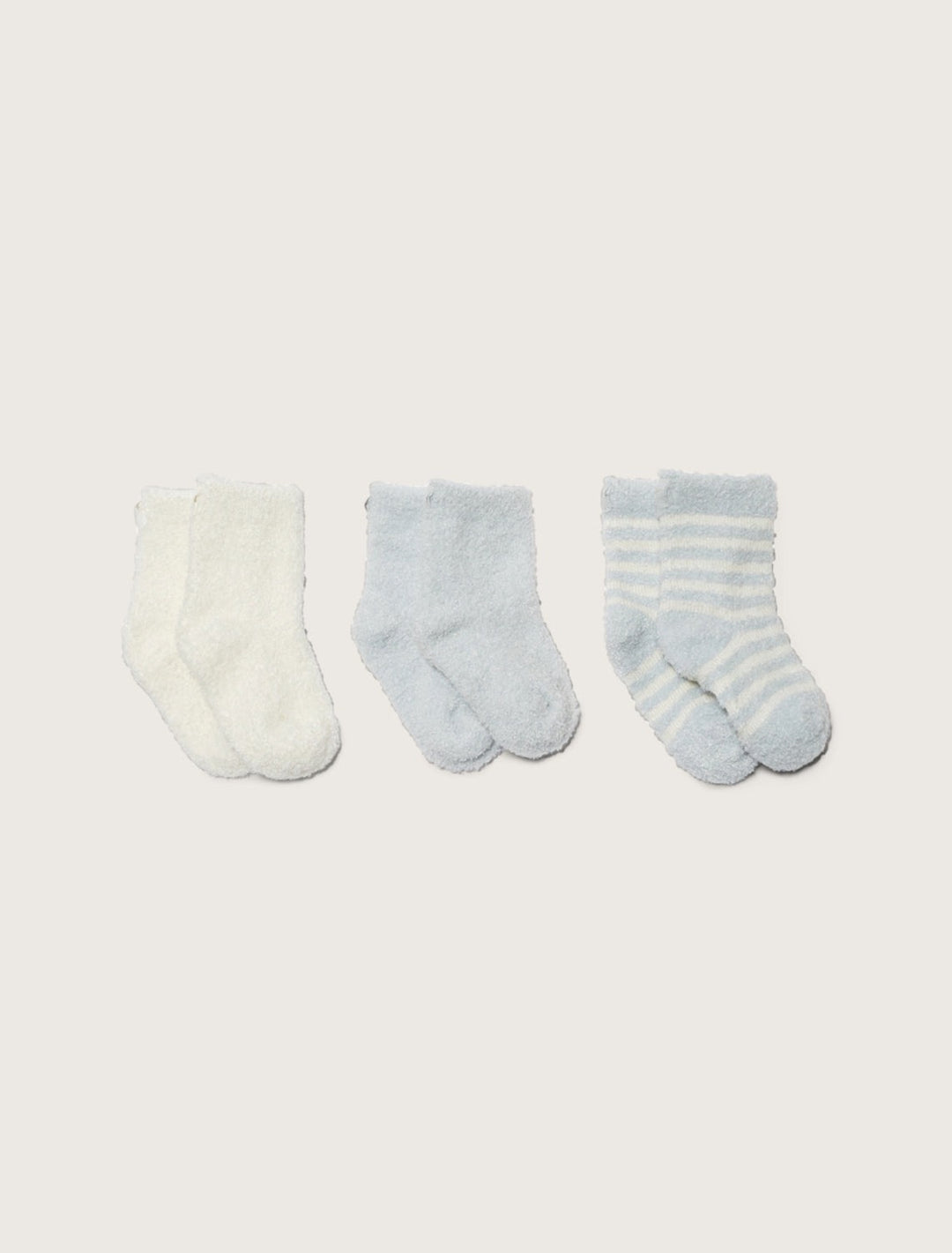 Set of three barefoot dreams infant socks in soft, colorful fabrics, perfect for gifting or keeping little feet cozy.