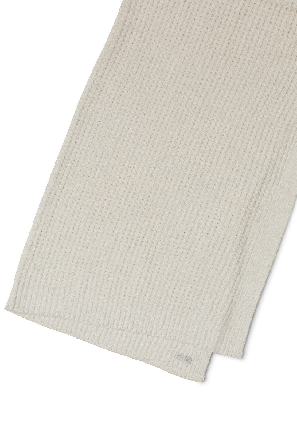 Soft beige barefoot dreams cozy waffle throw blanket draped over a sofa, showcasing its textured, plush fabric for home decor.