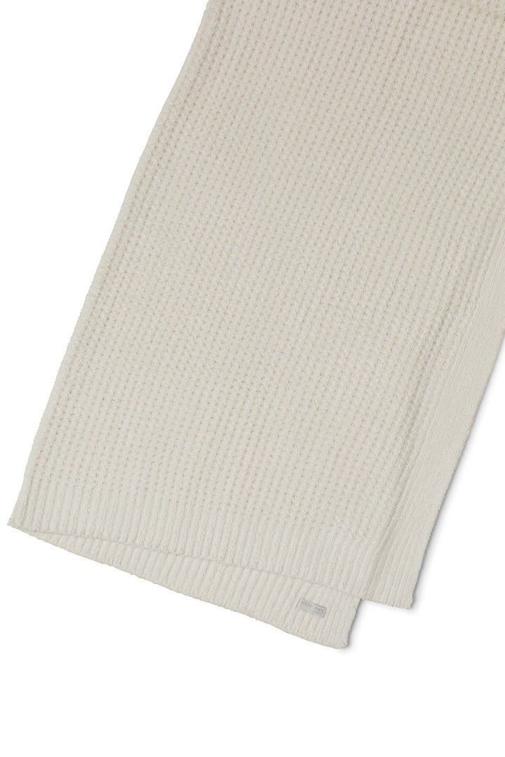 Soft beige barefoot dreams cozy waffle throw blanket draped over a sofa, showcasing its textured, plush fabric for home decor.