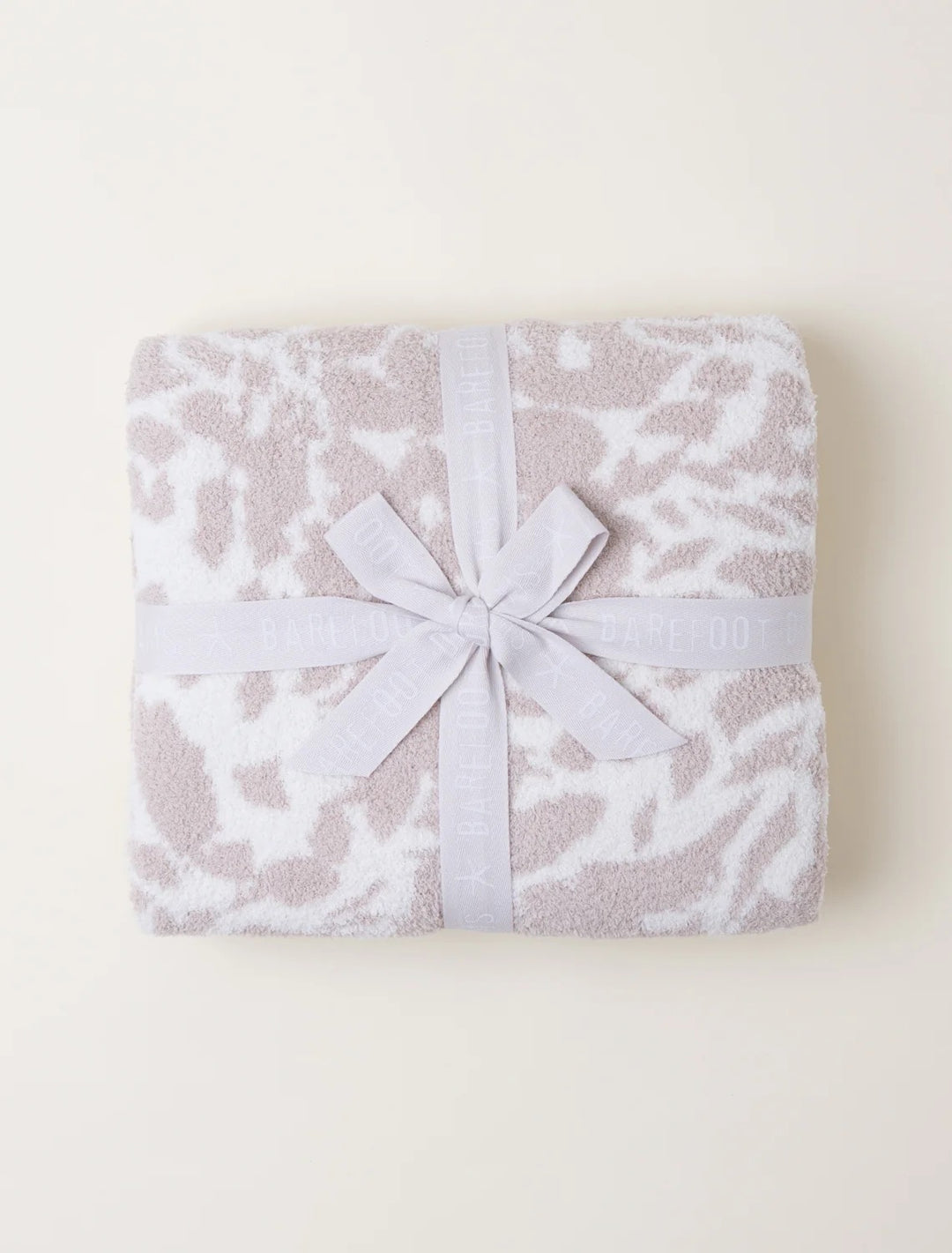 Soft Barefoot Dreams Blooms Blanket draped over a cozy living room sofa, showcasing its plush, floral-patterned design for home décor.