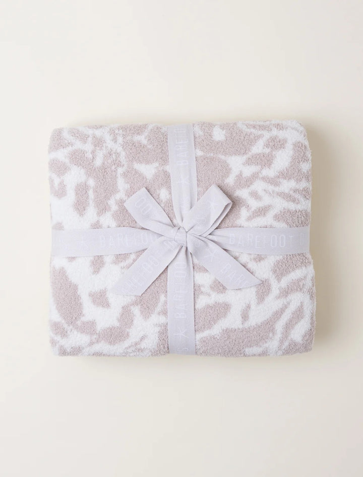 Soft Barefoot Dreams Blooms Blanket draped over a cozy living room sofa, showcasing its plush, floral-patterned design for home décor.