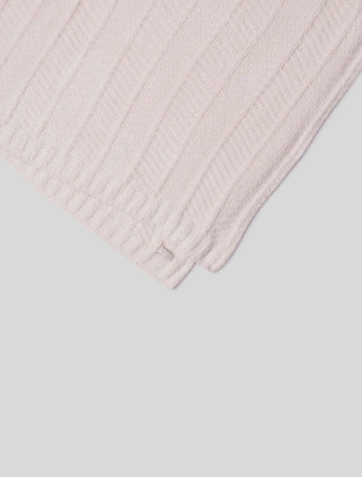 Barefoot Dreams cozy herringbone bed blanket draped over a bed, featuring soft, textured fabric in a warm, neutral tone.