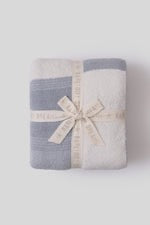 Barefoot Dreams Cozy Costa Block Throw blanket in soft, plush fabric displayed on a cozy living room sofa.