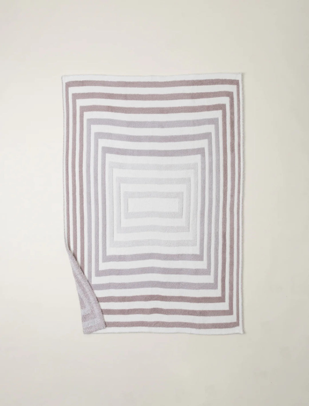 Barefoot Dreams Cozy Prismatic Throw blanket with colorful, soft knit fabric displayed draped over a couch in a cozy living room setting.