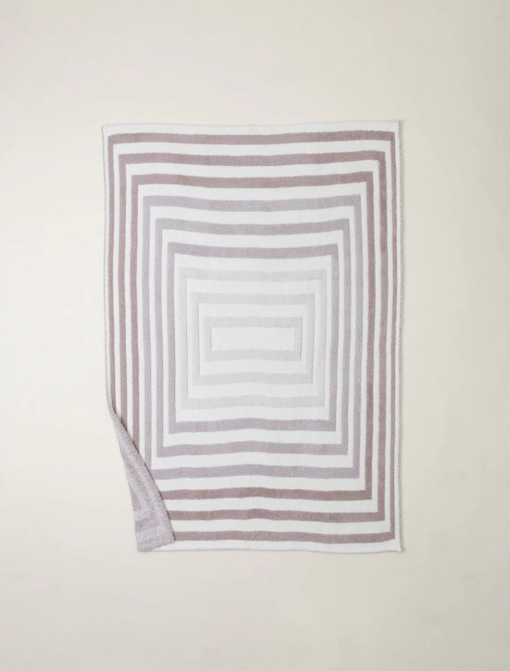 Barefoot Dreams Cozy Prismatic Throw blanket with colorful, soft knit fabric displayed draped over a couch in a cozy living room setting.