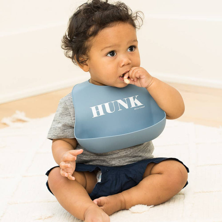 Baby wearing a Bella Tunno Hunk Wonder Bib, soft and colorful baby bib with adjustable straps for feeding and drool protection.