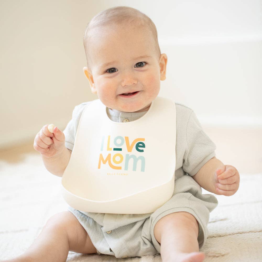 Baby wearing the Bella Tunno I Love Mom Wonder Bib with colorful design, soft fabric, and adjustable neck closure.