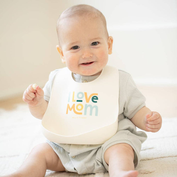 Baby wearing the Bella Tunno I Love Mom Wonder Bib with colorful design, soft fabric, and adjustable neck closure.