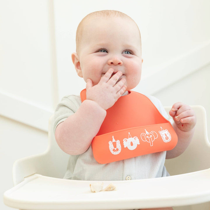Baby Bella Tunno Party Animals Starter Bib with colorful animal designs for infants, soft and adjustable for comfortable wear.
