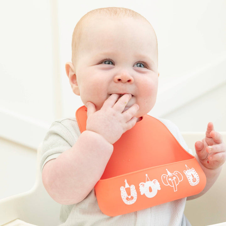 Baby Bella Tunno Party Animals Starter Bib with colorful animal design, soft fabric, and adjustable neck strap for infants.