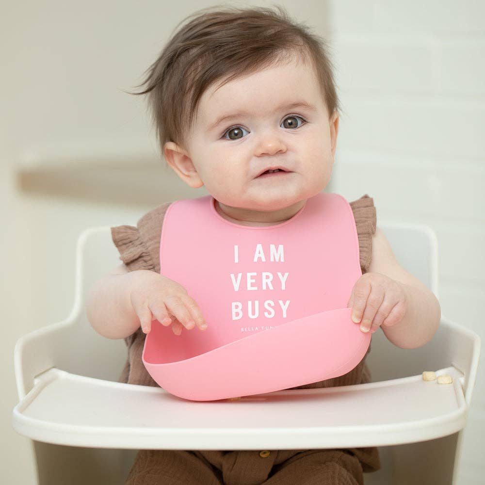 Baby wearing a Bella Tunno Very Busy Wonder Bib with colorful patterns, designed to keep clothes clean during feeding.