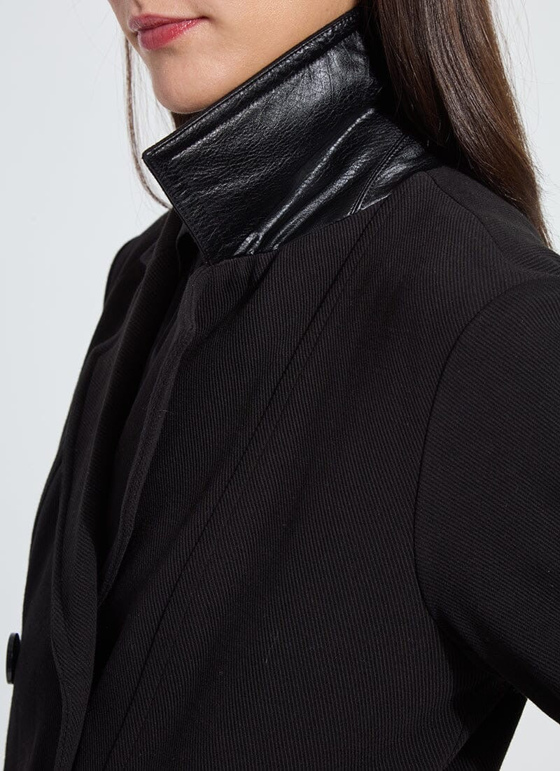 Close-up of a person wearing a black coat with a shiny collar against a white background