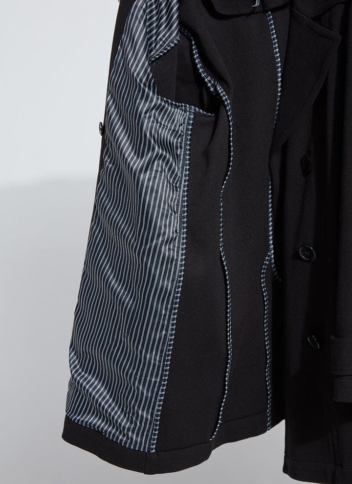 Close-up of a black coat with patterned lining on a light gray background