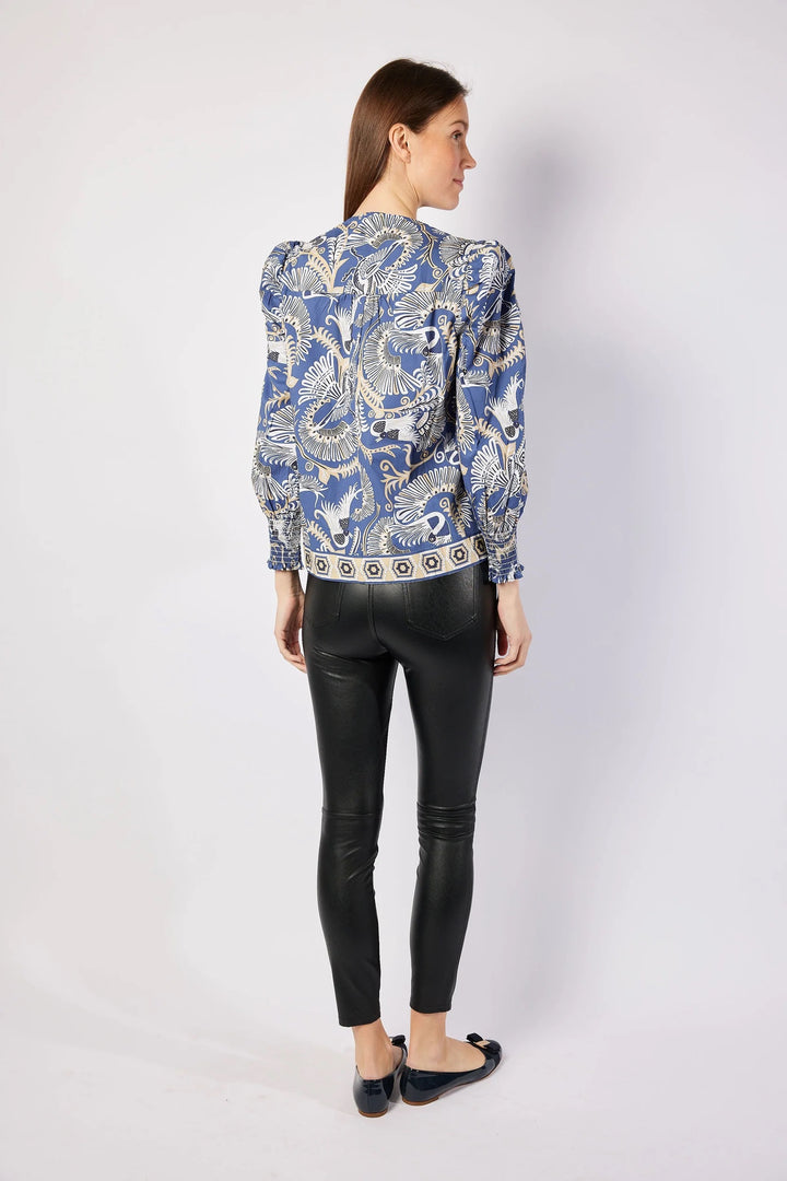 Woman wearing a blue patterned jacket and black leather pants on a white background