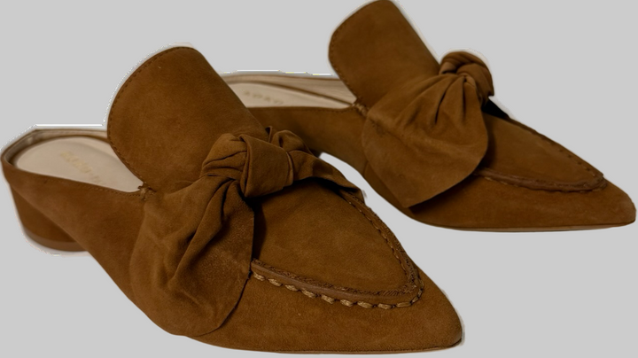 Brown suede mules with bow details on a white background