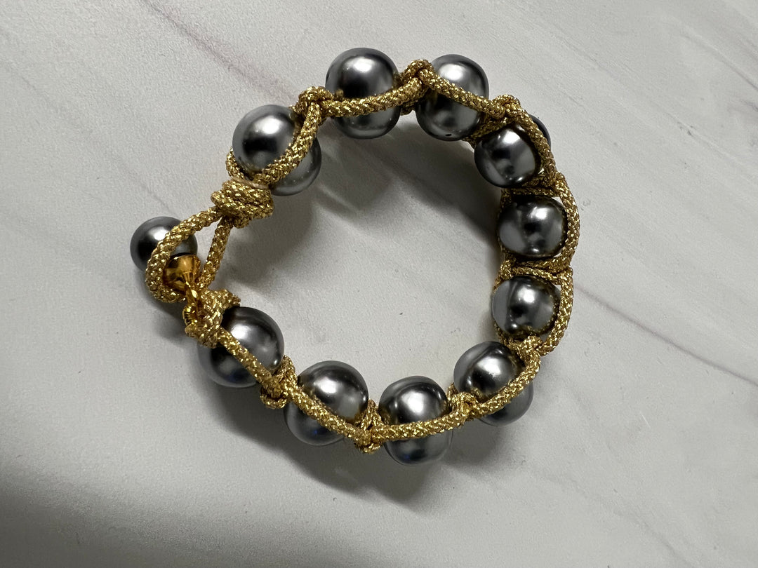 Pearl macrame bracelet with button clasp, handmade jewelry by Catherine Canino featuring white pearls and intricate knot design.