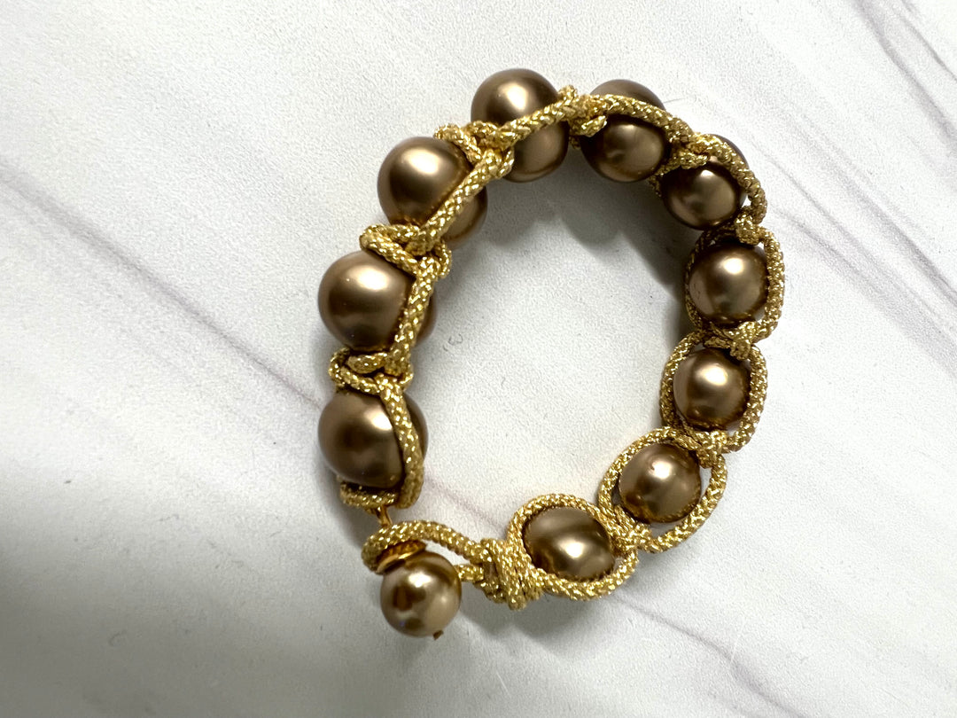Pearl macrame jewelry bracelet with button clasp by Catherine Canino, featuring white pearls and intricate knotting details.