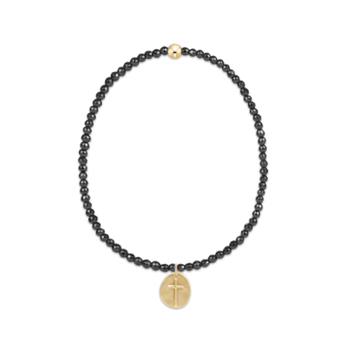 bracelet with hematite beads and gold cross pendant on a white background