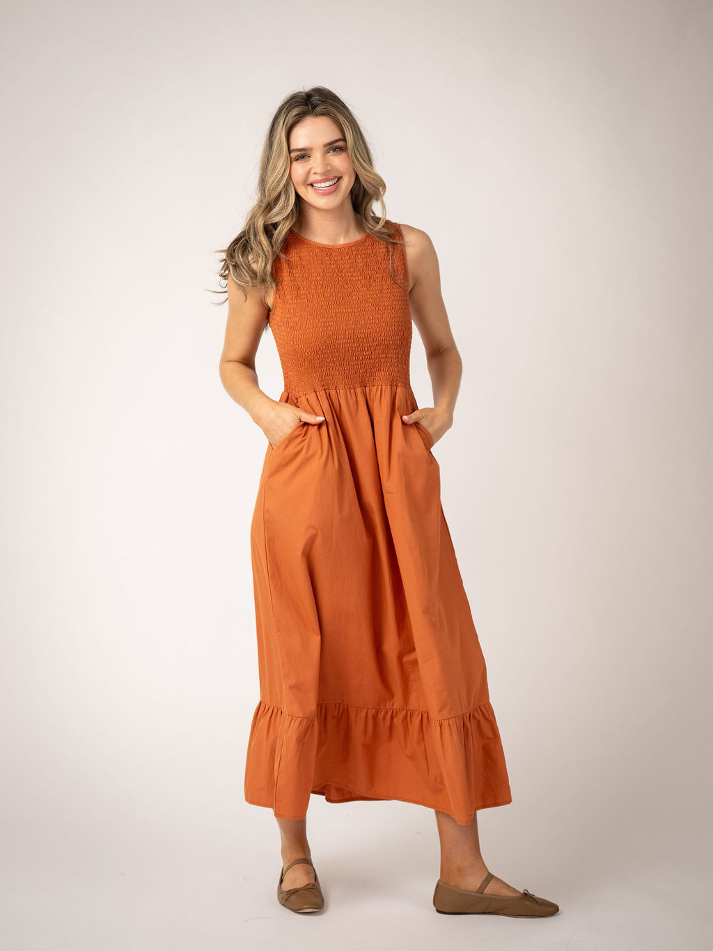 Beau and Ro Margot persimmon dress displayed on a hanger, showcasing its vibrant orange color and stylish design.