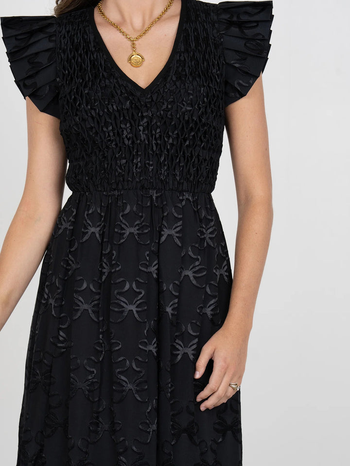 Emily McCarthy Grace Bow Lattice Midi Dress displayed on a model, showcasing its stylish bow details and lattice design.