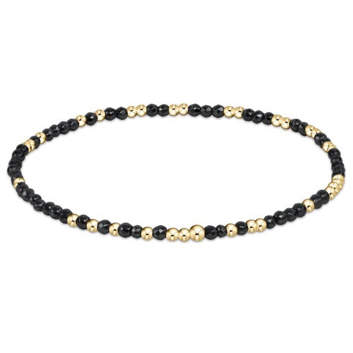 Enewton Hope Unwritten gemstone bracelet featuring colorful beads and a delicate charm on a soft fabric background.
