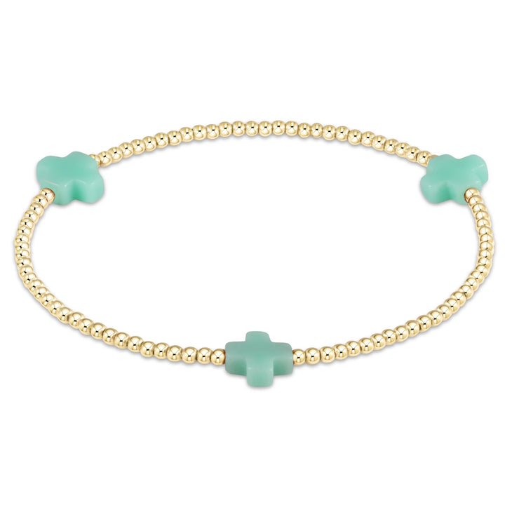 Enewton Signature Cross 2mm gold bracelet, close-up view showing polished gold links and detailed cross charm on accessory.